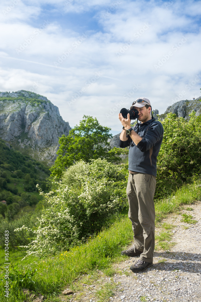 Tourist - Photographer shooting beautiful nature of Spain: Picos de Europa mountain peaks and tourist trails in summer sunny day with blue sky and clouds