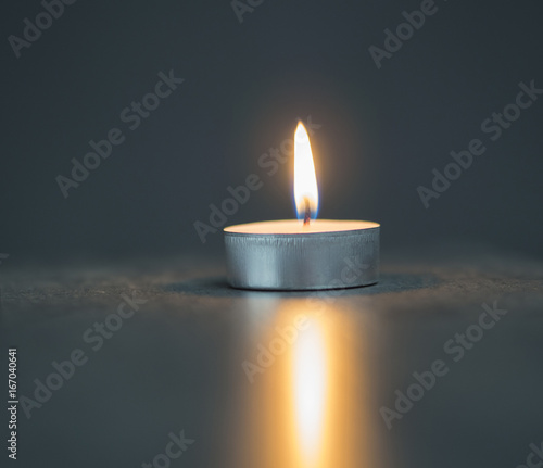 Obraz na plátně single tea light candle on the soft blurred grey background