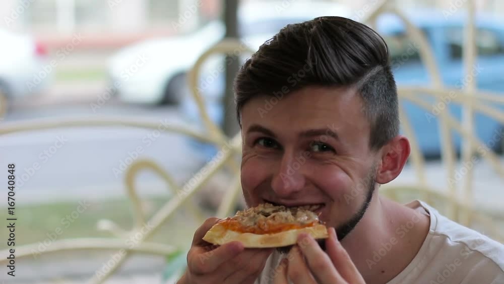 A man eating appetizing pizza. He is smiling and looking at the camera A man eating appetizing pizza. He is smiling and looking at the camera