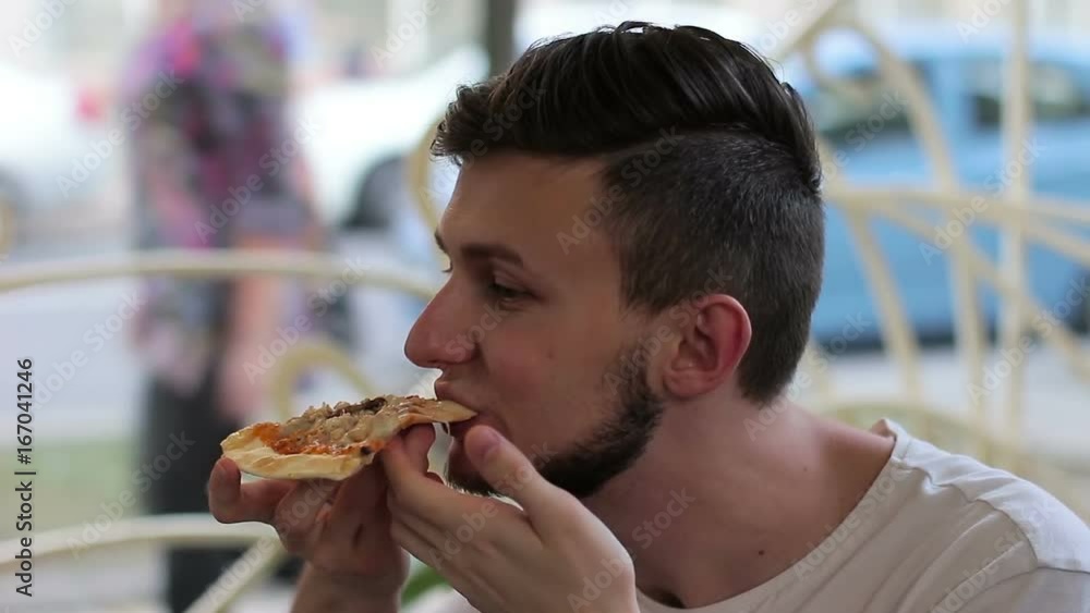 Young man eating pizza in a cafe on the street Young man eating pizza in a cafe on the street