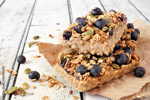 Fotografi Two stacked superfood breakfast bars with oats and blueberries, side view on rus