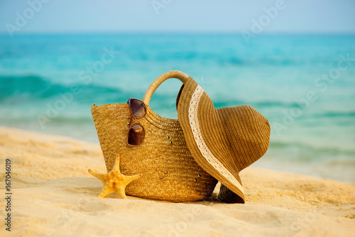 Bag of hat and glasses on the beach.