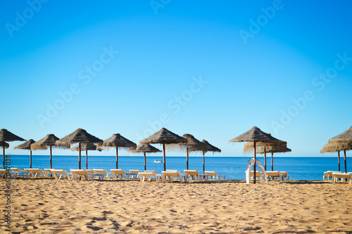 Fototapeta Naklejka Na Ścianę i Meble -  Sunny sky and chairs with parasol on the beautiful beach of Portugal