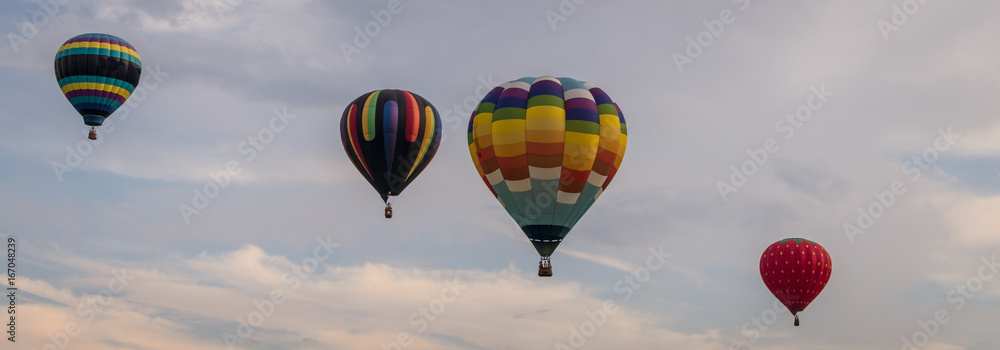 Fototapeta premium Colorful array of hot air balloons float through the sky at dusk for banner
