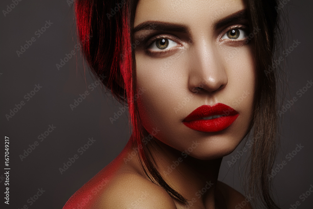 Fototapeta premium Beautiful model with fashion make-up. Portrait sexy woman with glamour red lips makeup, strong eyeshadows, hairstyle
