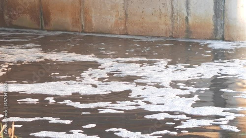 Foam on the water after a small hydroelectric station. Water passes concrete dam photo