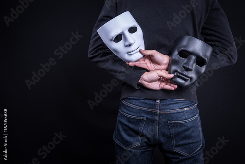 Mystery man holding black and white mask. Anonymous social masking concept. photo