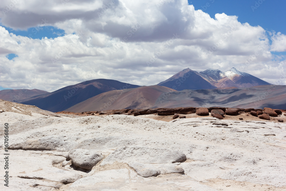 Colorful landscape with volcanic mountain snow peak under cloudy sky. Salt flats, red rocks and volcanic mountains of San Pedro de Atacama, Chile, South America.