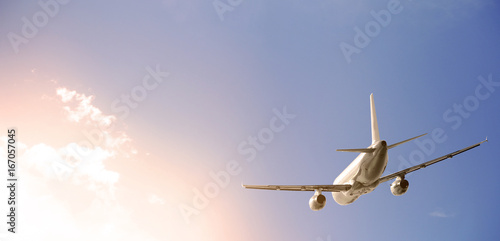 Airplane is flying past clouds in a blue sky
