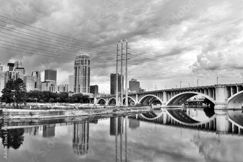 Cloudy morning in Minneapolis. Minneapolis downtown skyline and Third Avenue Bridge above Saint Anthony Falls, Mississippi river in black and white, Midwest USA, Minnesota state.