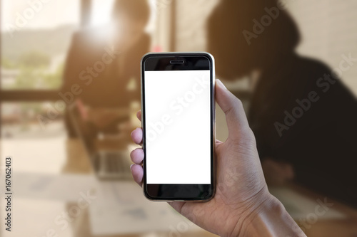 Close up man hold smartphone with blank screen mobile and business discussion in office blurred background.