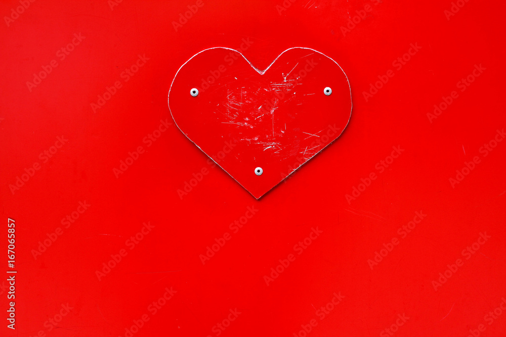 Scratched red metal heart on red background