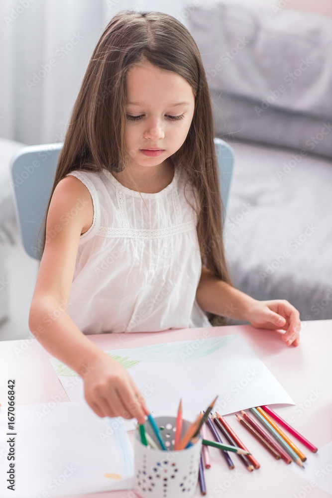 Cute little girl is drawing while spending time at home
