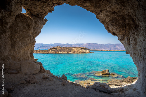 Amazing view through a cave of Koufonisi island with magical turquoise waters, lagoons, tropical beaches of pure white sand and ancient ruins on Crete, Greece