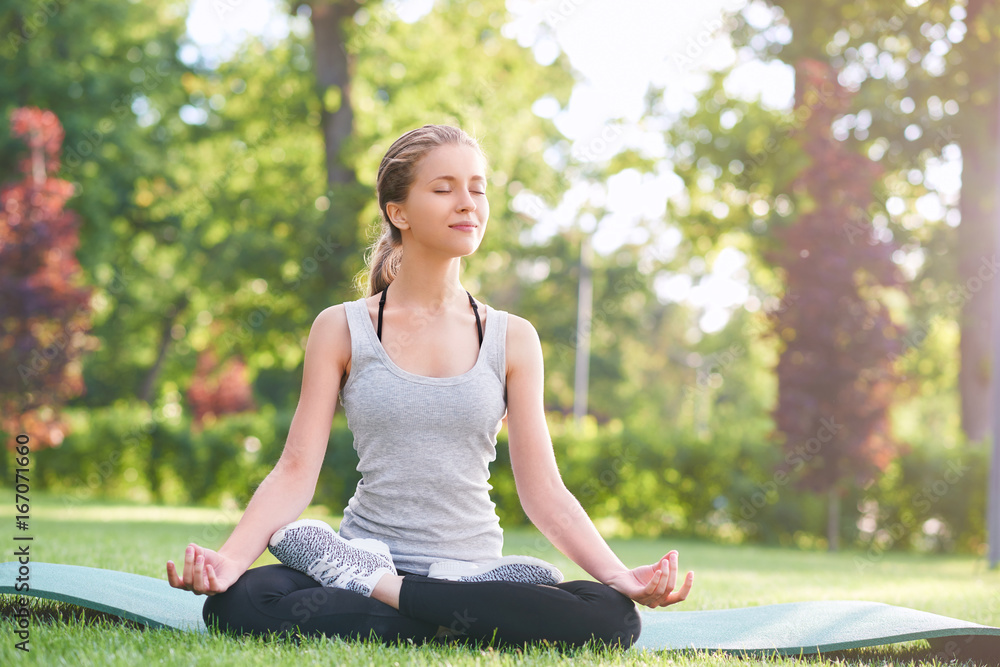 Shot of a young beautiful woman smiling with her eyes closed sitting in lotus position at the local park meditating copyspace sport lifestyle healthcare happiness vitality yoga concept. Shot of a young beautiful woman smiling with her eyes closed sitting in lotus position at the local park meditating copyspace sport lifestyle healthcare happiness vitality yoga concept.