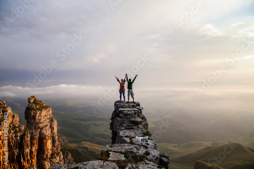 Beautiful couple standing on the cliff oi the mountain