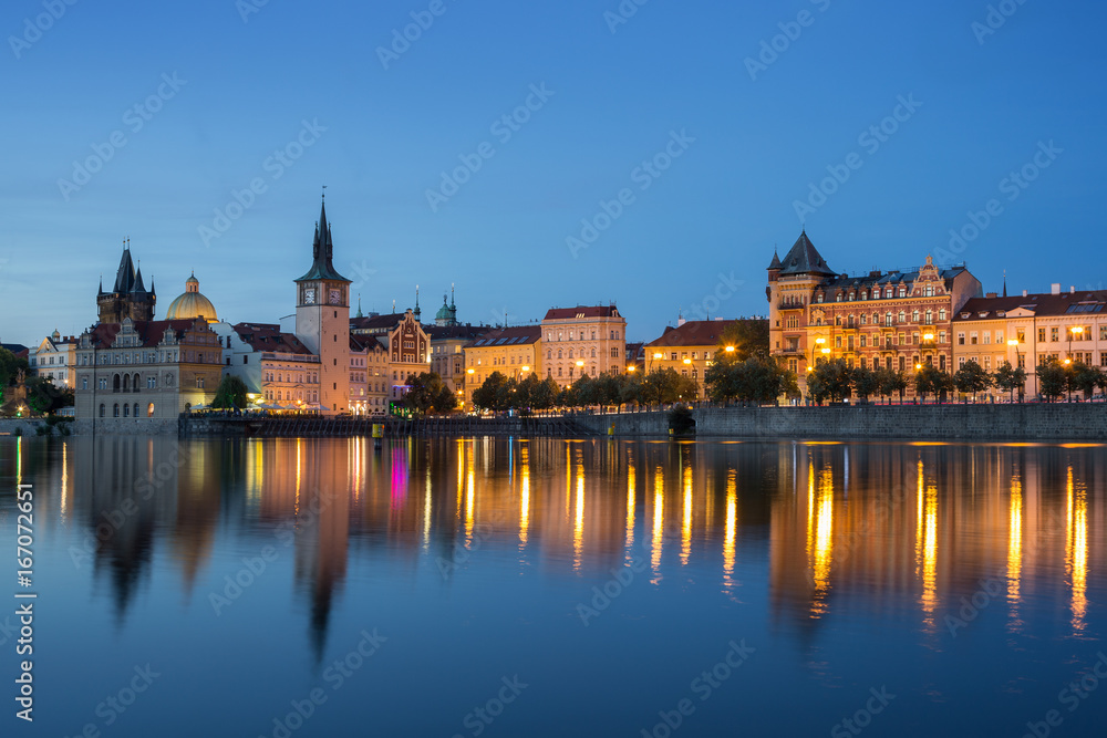Lit old buildings at the Old Town and their reflections on the Vltava River in Prague, Czech Republic, at dusk.