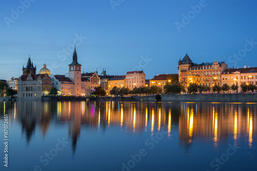 Lit old buildings at the Old Town and their reflections on the Vltava River in Prague, Czech Republic, at dusk.