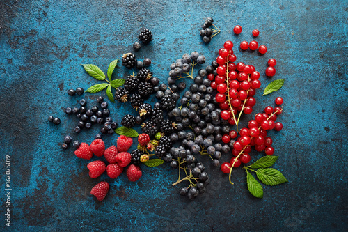 Mix of fresh berries with leaves on textured metal background
