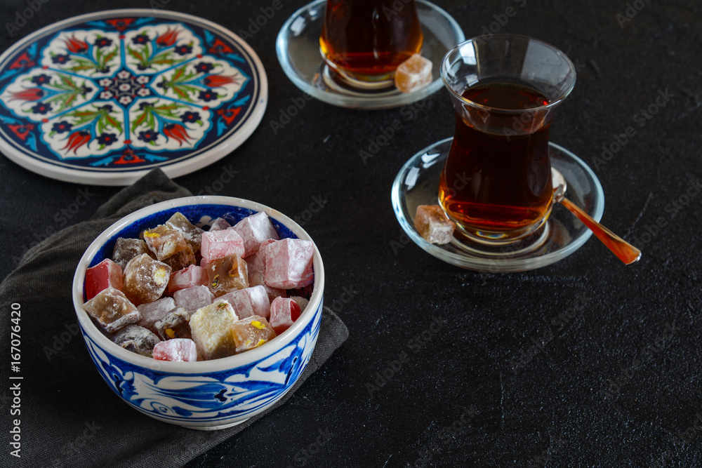 Delicious Turkish delight with tea on a black background. Turkish lukum. Delicious Turkish delight with tea on a black background. Turkish lukum.