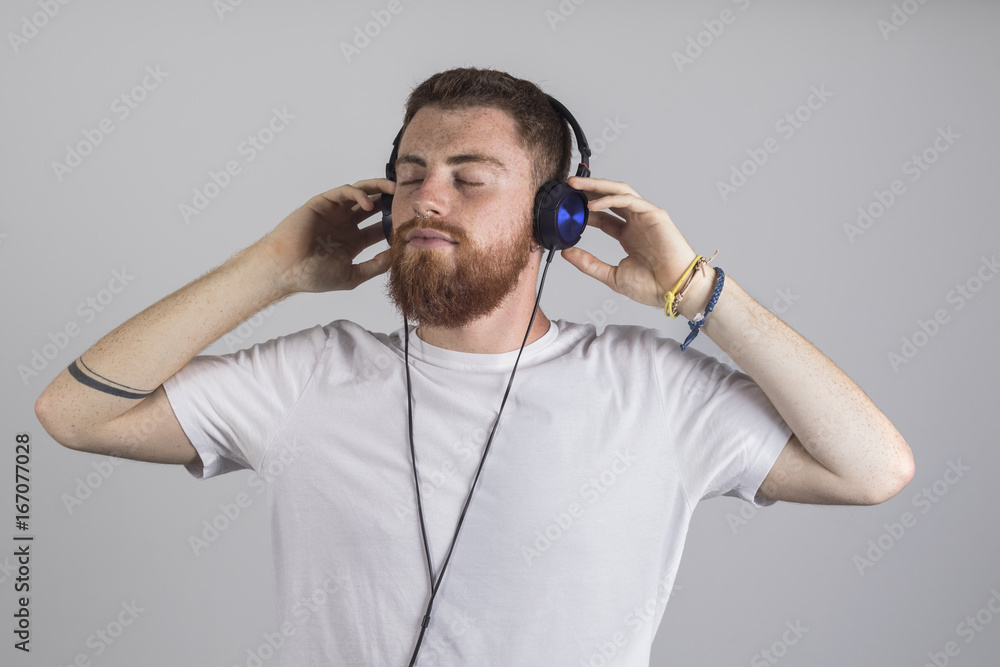 Hombre joven pelirrojo escuchando musica Hombre joven pelirrojo escuchando musica
