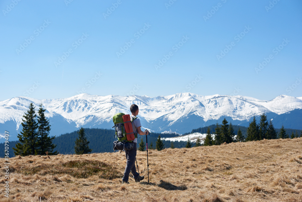 A man hiker with a backpack admiring the view walking in the mountains using hiking sticks copyspace achieving equipment athletic sportive lifestyle active
