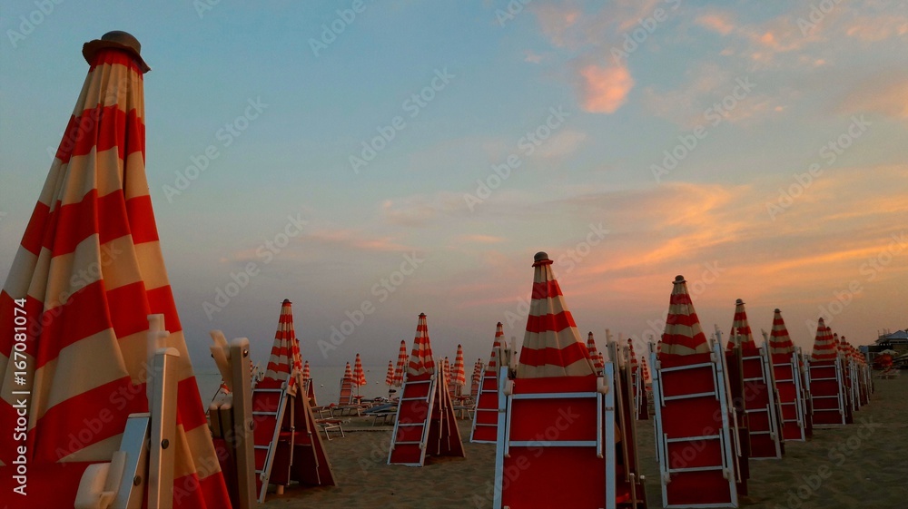 Ombrelloni in spiaggia al tramonto - obrazy, fototapety, plakaty 