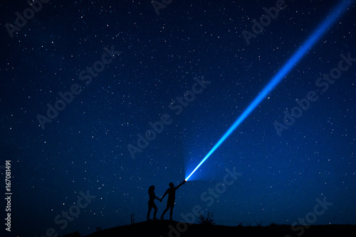 Couple in love walks under the stars. Silhouette of lovers couple who are enjoying their time together at night under a starry sky. Starry sky. Night walk. Man and woman traveling