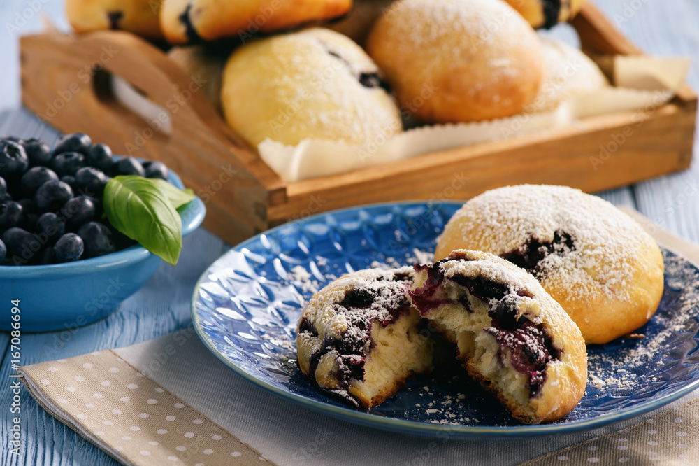 Homemade blueberry filled buns on wooden table.