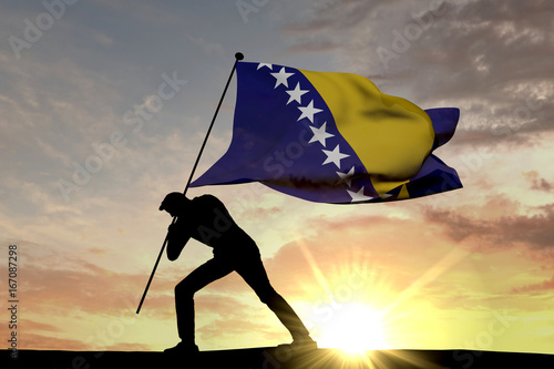 Valokuva Bosnia flag being pushed into the ground by a male silhouette