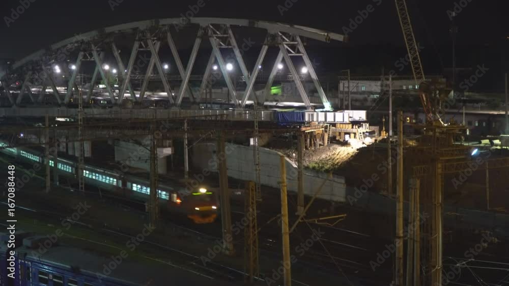 The construction of a steel bridge and night movement of trains on a railway junction The construction of a steel bridge and night movement of trains on a railway junction