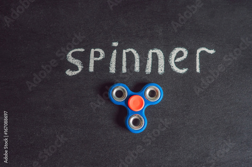 Famous fidget spinner stress relieving n a black wooden background. And the inscription spinner photo