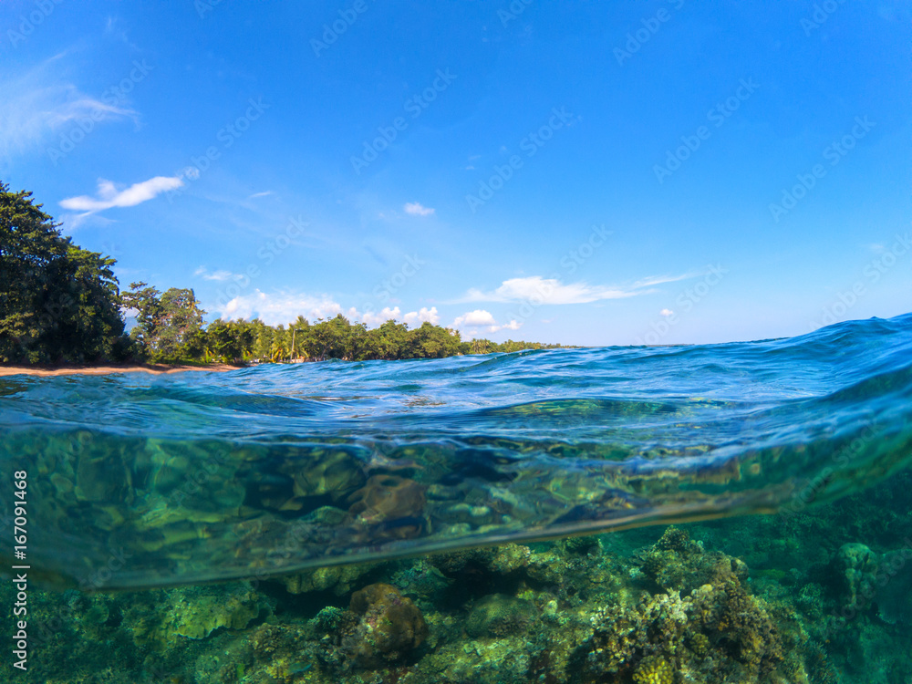 Split landscape with sea and sky. Split photo with tropical island and underwater coral reef.