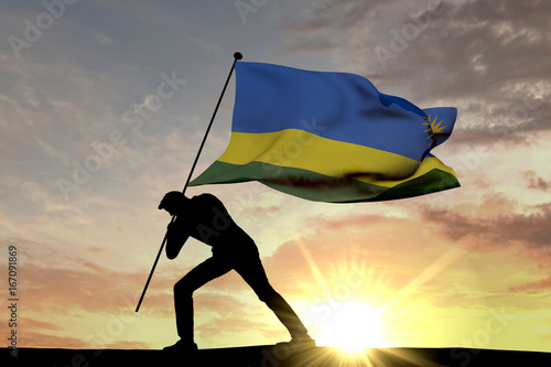 Rwanda flag being pushed into the ground by a male silhouette. 3D Rendering