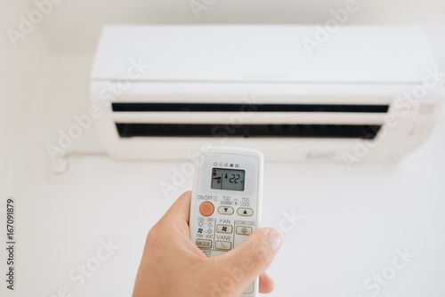 Hand adjusting temperature of home air conditioner