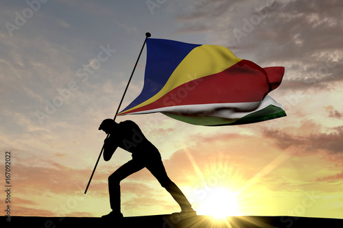 Seychelles flag being pushed into the ground by a male silhouette. 3D Rendering