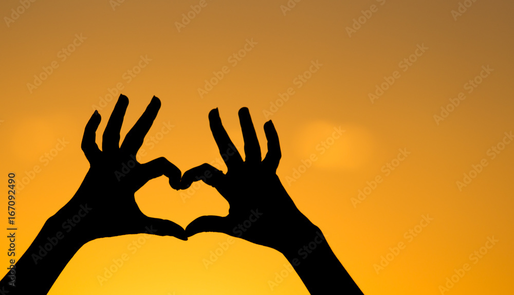 Silhouette of the heart by hands at sunset