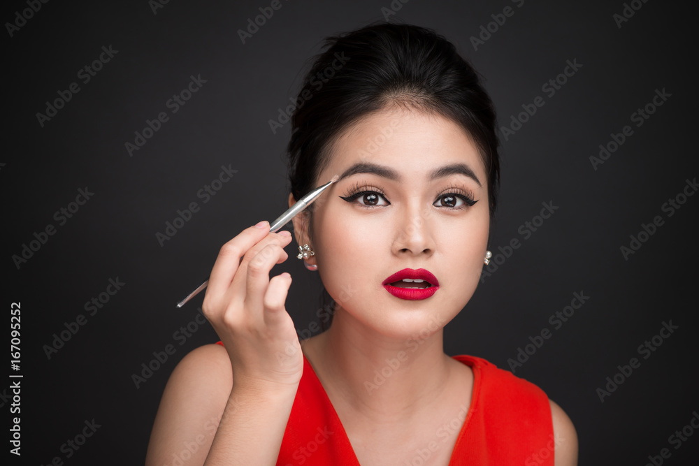 Close up of beautiful face of young asian woman applying eyeshadow on her eyebrow with brush Close up of beautiful face of young asian woman applying eyeshadow on her eyebrow with brush