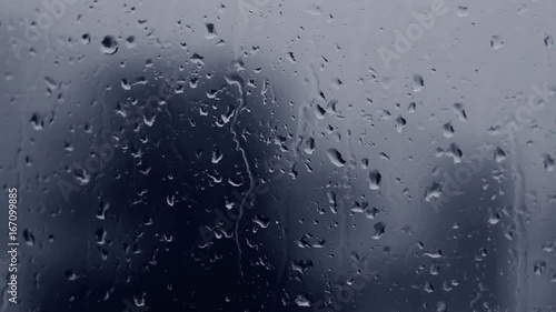 Dark blue rain drops on window glass.