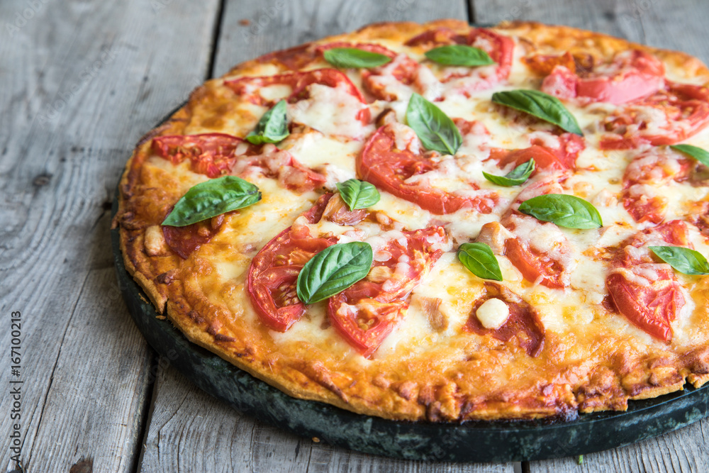 Hot Homemade Pepperoni Pizza on a rustic wooden table. Pizza with tomato, cheese and basil with copy space Hot Homemade Pepperoni Pizza on a rustic wooden table. Pizza with tomato, cheese and basil with copy space