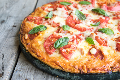 Hot Homemade Pepperoni Pizza on a rustic wooden table. Pizza with tomato, cheese and basil with copy space