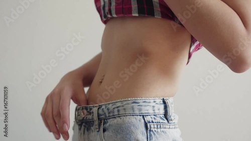 Young girl in casual clothes, shows her flat sporty belly with piercing. Close up healthy stomach
