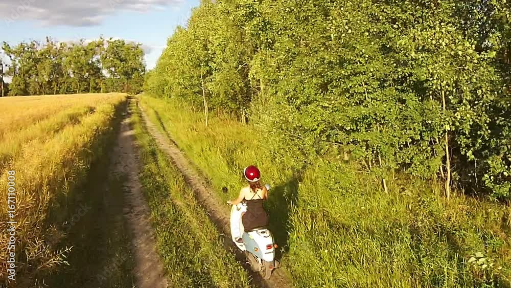 A girl riding a scooter on a country road A girl riding a scooter on a country road