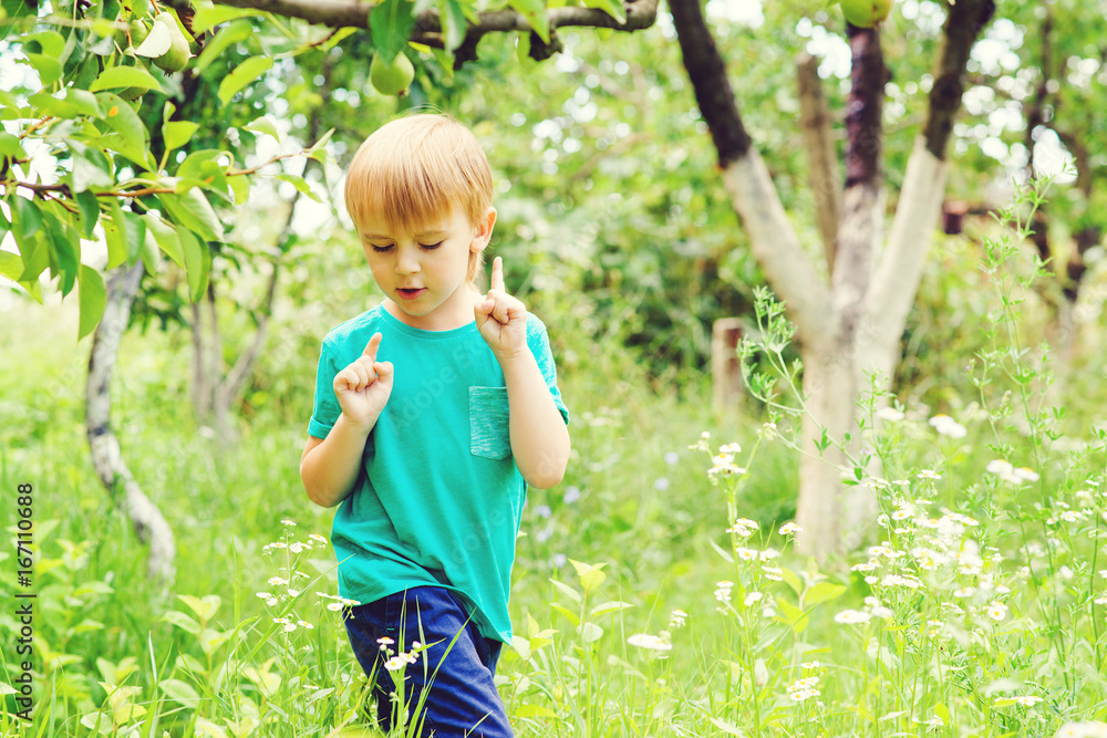 Curious blond boy catching insects in garden. Cute child having fun outdoor. Curious blond boy catching insects in garden. Cute child having fun outdoor.