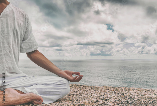 Canvas Print Man meditating on a high cliff above the sea in the Lotus position