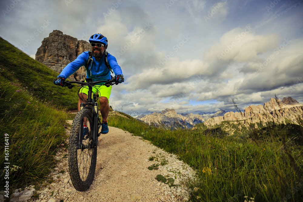 View of cyclist riding mountain bike on single trail in Dolomites, Cinque Torri, South Tirol, Italy View of cyclist riding mountain bike on single trail in Dolomites, Cinque Torri, South Tirol, Italy