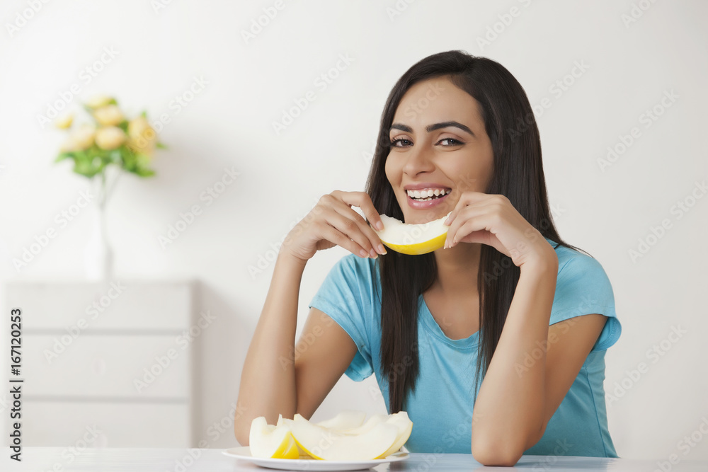 Smiling young woman holding slice of melon at home Smiling young woman holding slice of melon at home