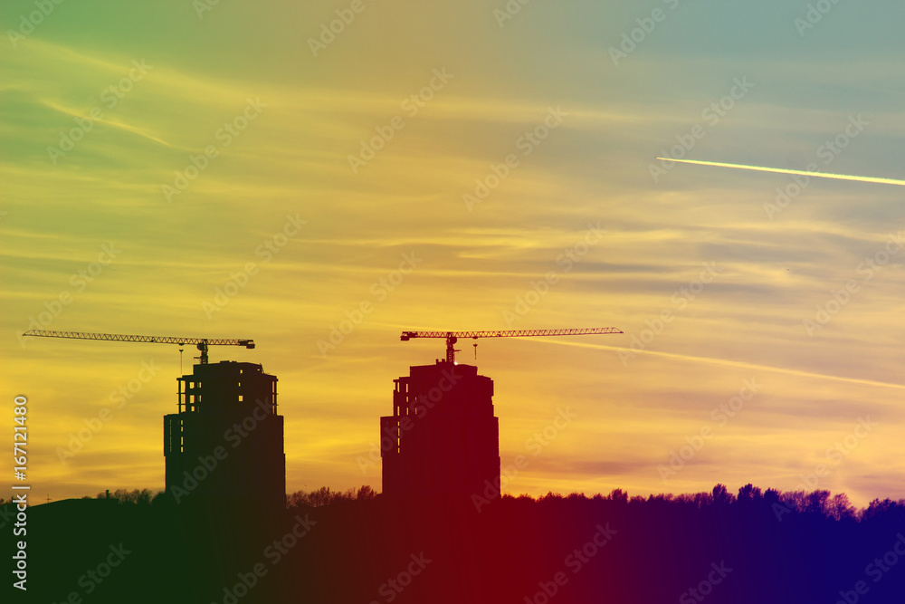 Silhouettes of houses under construction with cranes on sunset background. Retro style.