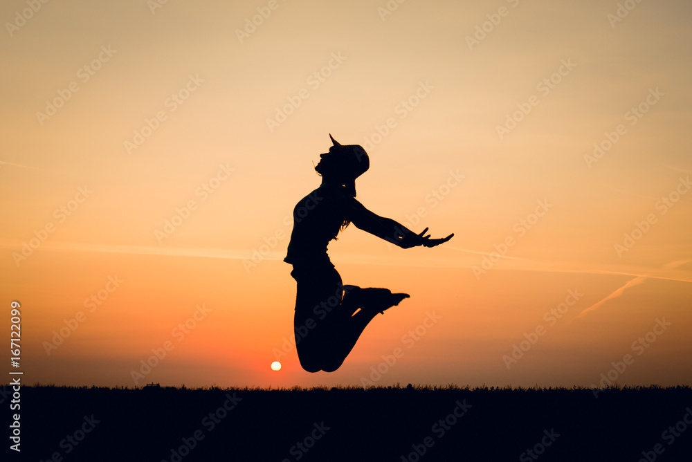 Joyful girl jumping at sunset. Silhouette