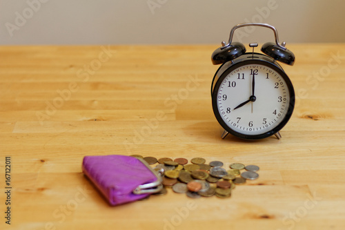 Zegar i portfel z pieniędzmi na drewnianym stole